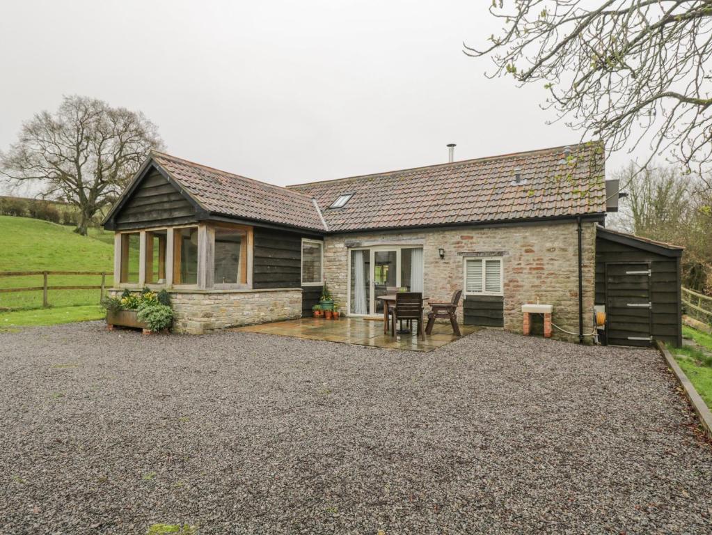 a brick house with a patio in front of it at Oxbarton in Butcombe