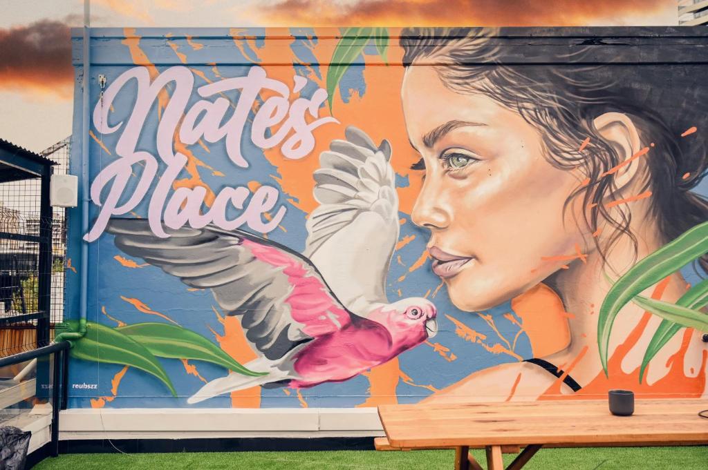 a mural of a woman and a pink bird at Nate's Place Backpackers Sydney in Sydney