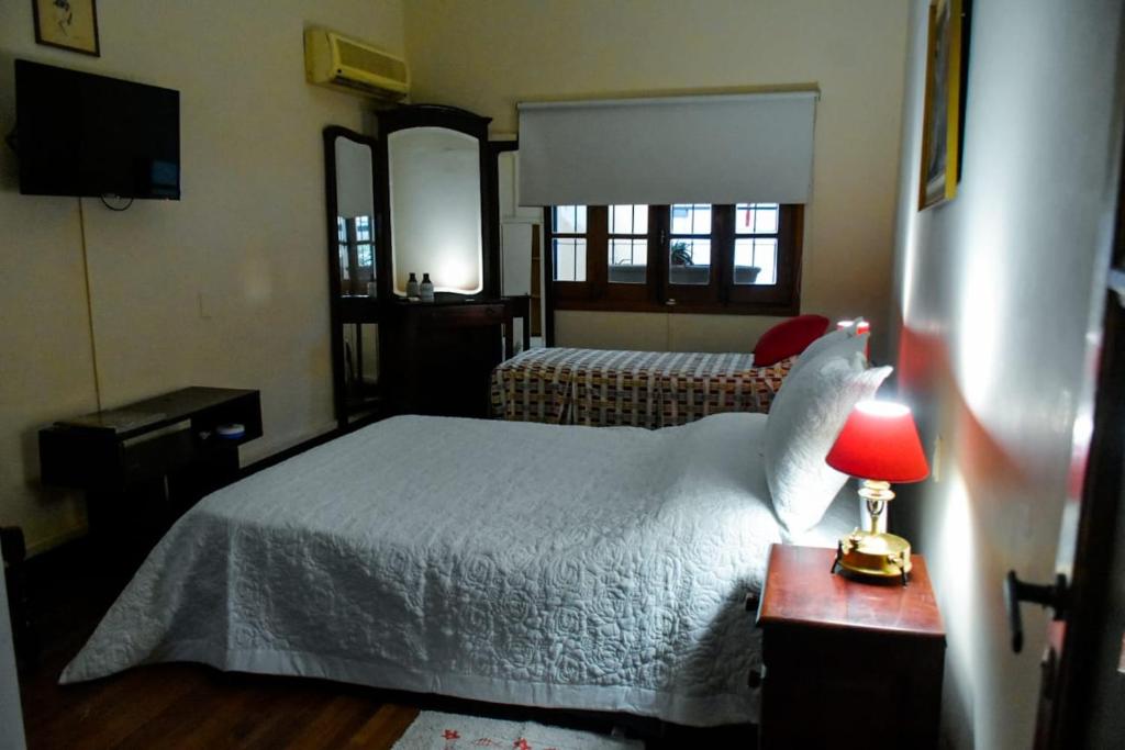 a bedroom with a white bed and a red lamp at Lo de Poujade in Posadas