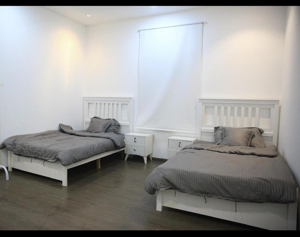 شقة جديدة ومفروشة للايجار اليومي والشهري في محافظة الرس في الرس: سريرين في غرفة بجدران بيضاء