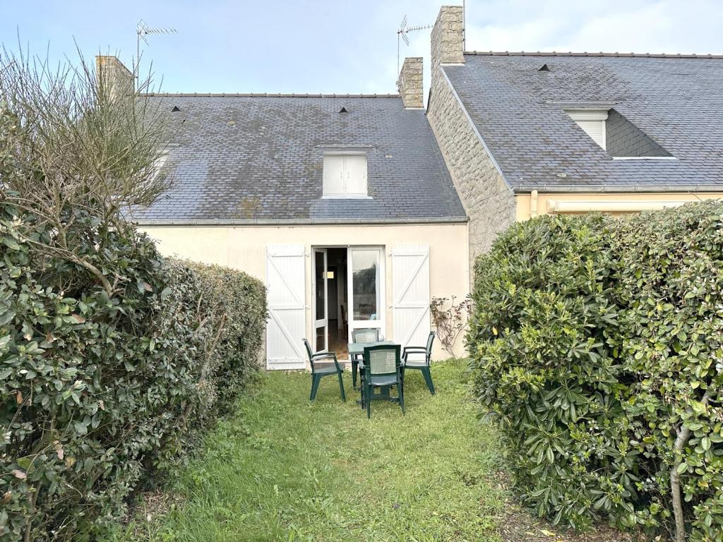 une maison avec deux chaises et une table dans la cour dans l'établissement Maison cosy à 300m de la plage du Fogeo, équipements modernes et parking privé - FR-1-639-91, à Arzon