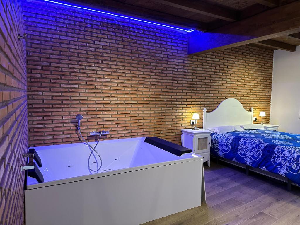 bañera grande en una habitación con cama en Apartamentos A Fala en Trevejo y San Martin de Trevejo, Sierra de Gata, en Trevejo