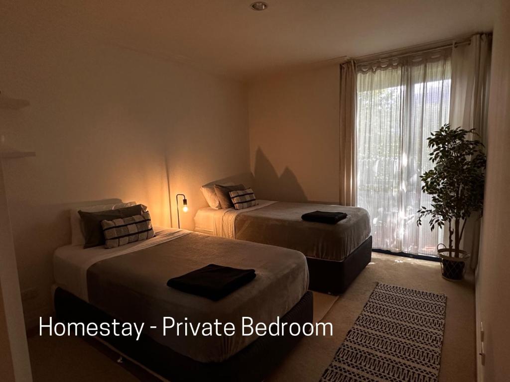 Homestay - Yarra River Boulevard في ملبورن: غرفة نوم بسريرين ونافذة