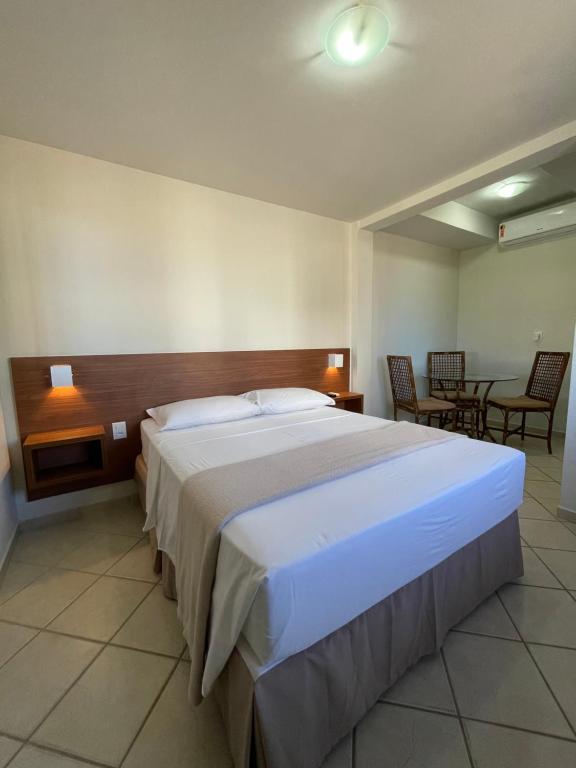 a bedroom with a large bed and a table and chairs at Pousada Laranja - Nova Administração in Natal