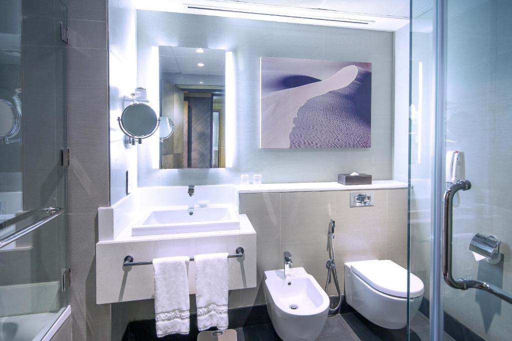 a bathroom with a sink and a toilet and a mirror at Ayla Bawadi Hotel & Mall in Al Ain
