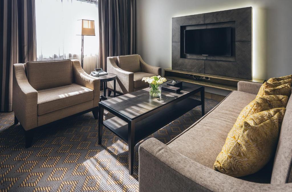 a living room with a couch and chairs and a tv at Ayla Bawadi Hotel & Mall in Al Ain