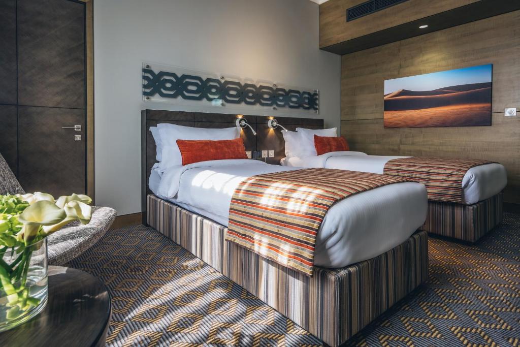 a hotel room with two beds and a couch at Ayla Bawadi Hotel & Mall in Al Ain
