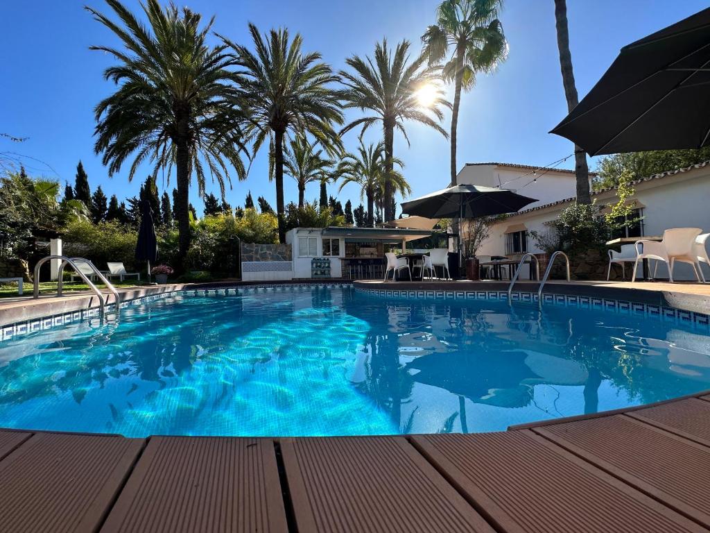 ein großer Pool mit Palmen im Hintergrund in der Unterkunft Banus Lodge in Marbella