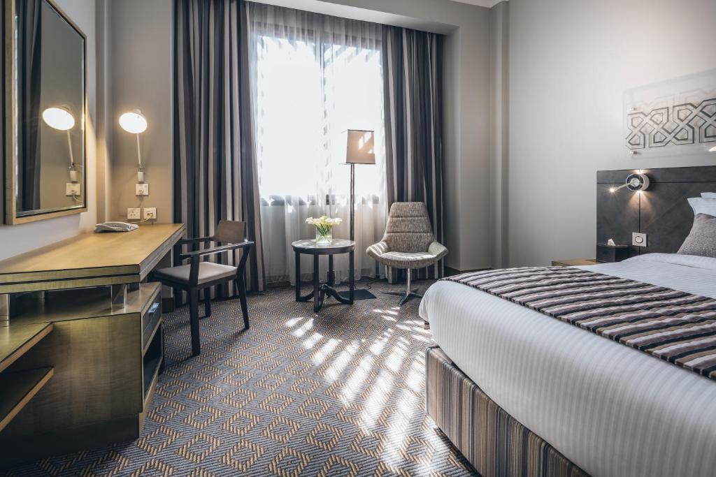 a hotel room with a bed and a desk at Ayla Bawadi Hotel & Mall in Al Ain