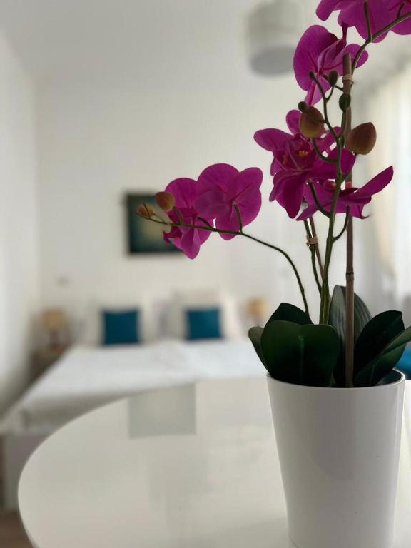 un jarrón blanco con flores púrpuras en una mesa en Fior di Loto Suite - Antonelli, en Turín