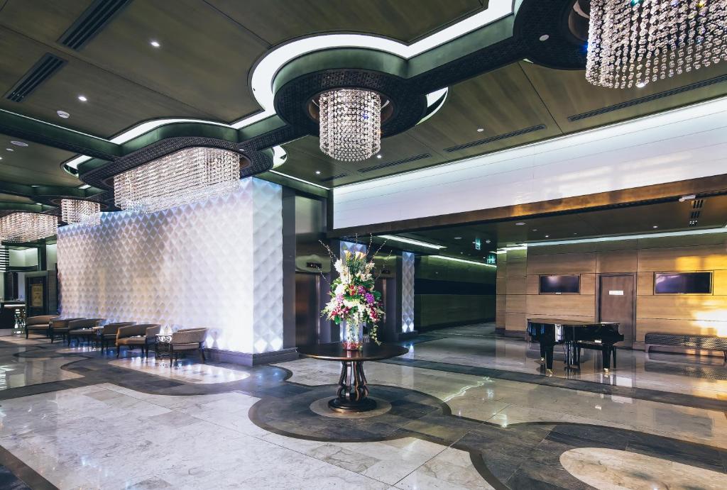 a lobby with chairs and a table with flowers at Ayla Bawadi Hotel & Mall in Al Ain