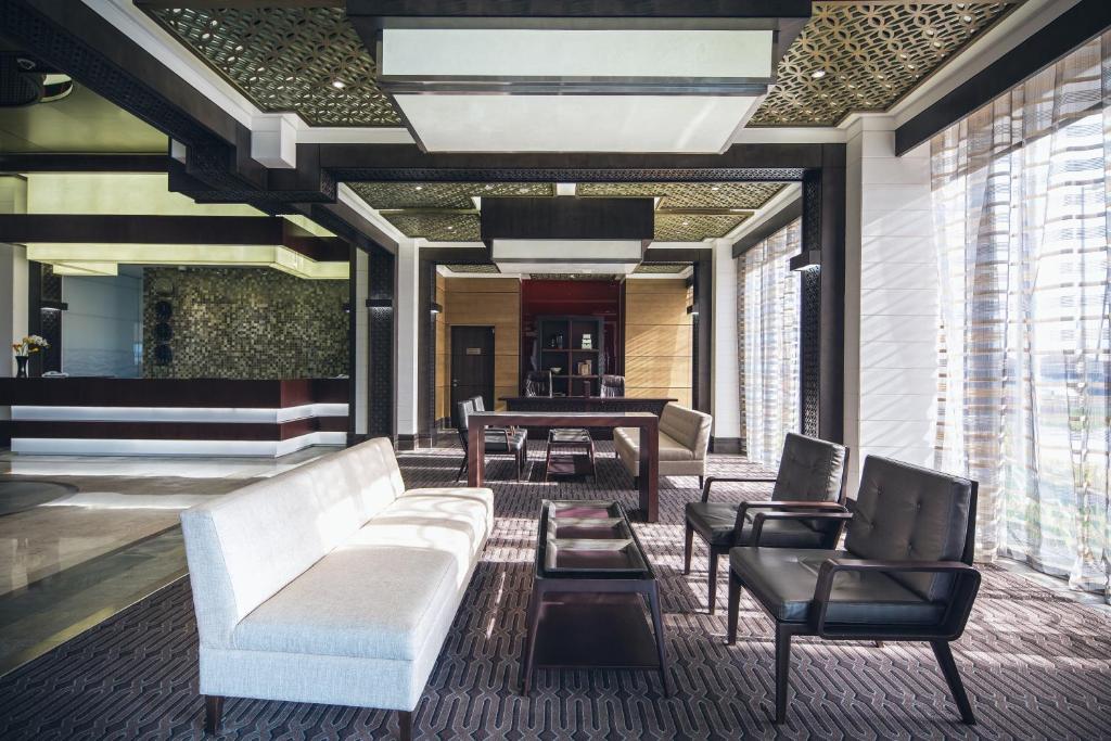 a lobby with a white couch and chairs and a piano at Ayla Bawadi Hotel & Mall in Al Ain