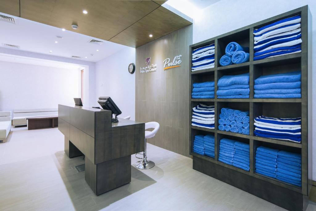 an office with a desk and a room with blue towels at Ayla Bawadi Hotel & Mall in Al Ain