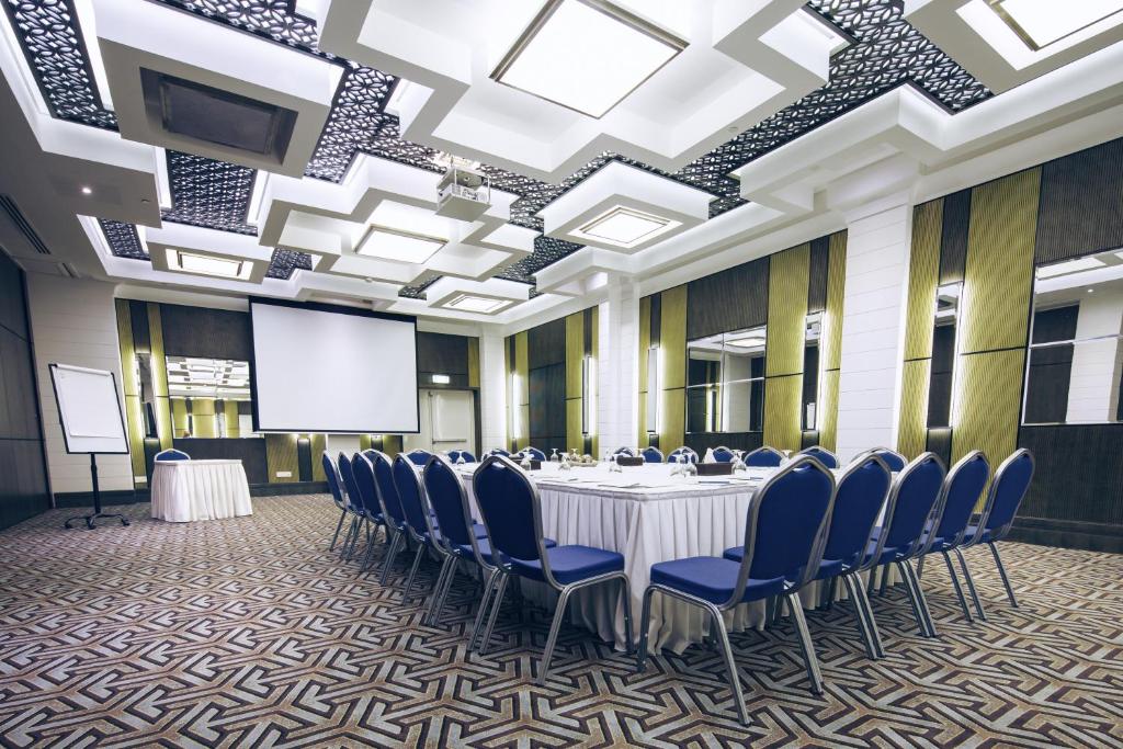 a conference room with a table and chairs and a projection screen at Ayla Bawadi Hotel & Mall in Al Ain