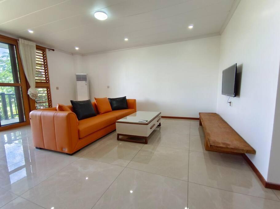 a living room with an orange couch and a tv at 2 bedroom Apartment in Nadi