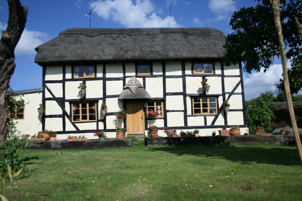 a white and black house with a thatched roof at The Cobblers Bed and Breakfast in Bishampton