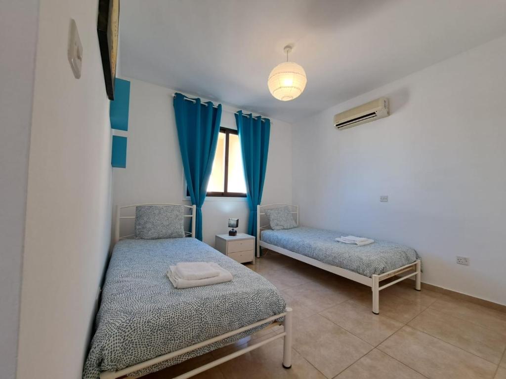 a bedroom with two beds and blue curtains at AFRODITI APARTMENTs in Perivolia