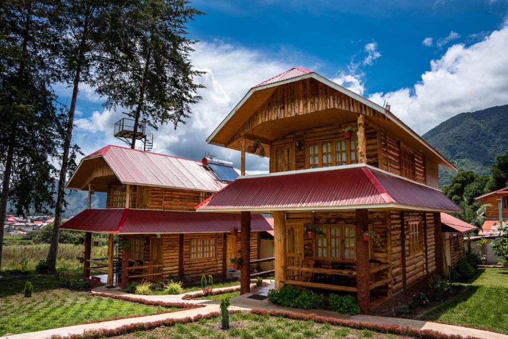 a large wooden house with a red roof at Fundo Hassinger in Oxapampa