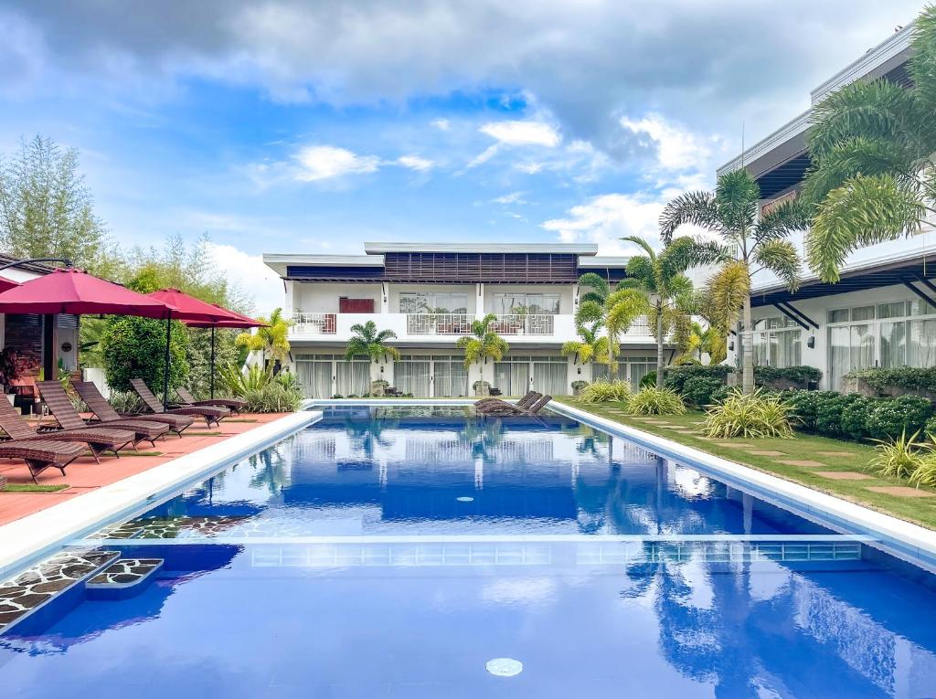 a pool at a resort with chairs and a building at Bella Napoli Resort & Resto in Panglao