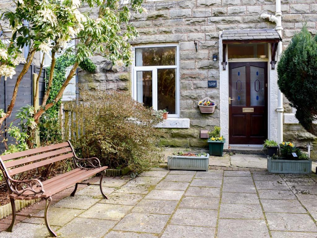 eine Holzbank vor einem Haus mit einer Tür in der Unterkunft Ivy Cottage in Newchurch