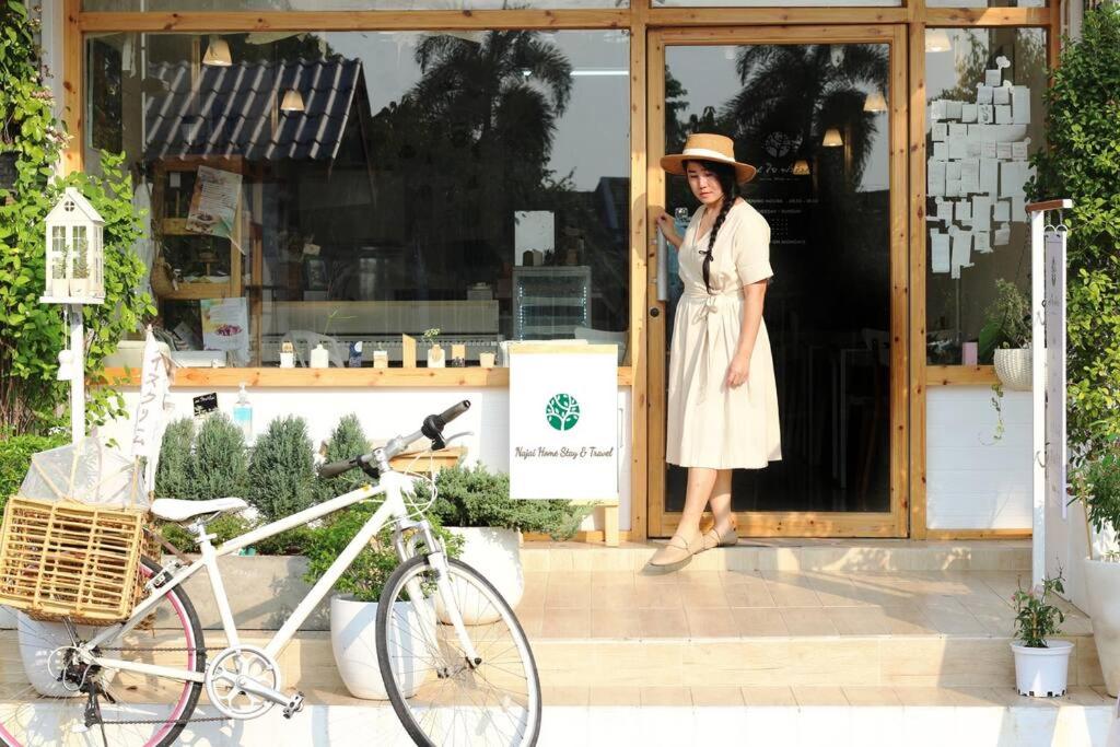 ランプーンにあるNajai Home Stay lamphunの自転車を持つ店の出入り口に立つ女