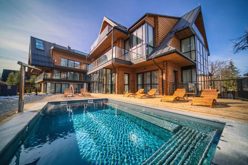 a house with a swimming pool in front of a house at Lipowy Dwór in Zakopane