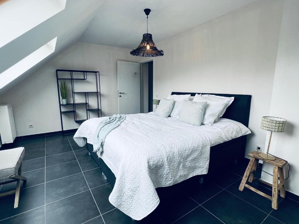 een slaapkamer met een groot bed met witte lakens en kussens bij ZEN op Vakantie - Zen aan De Gavers in Onkerzele