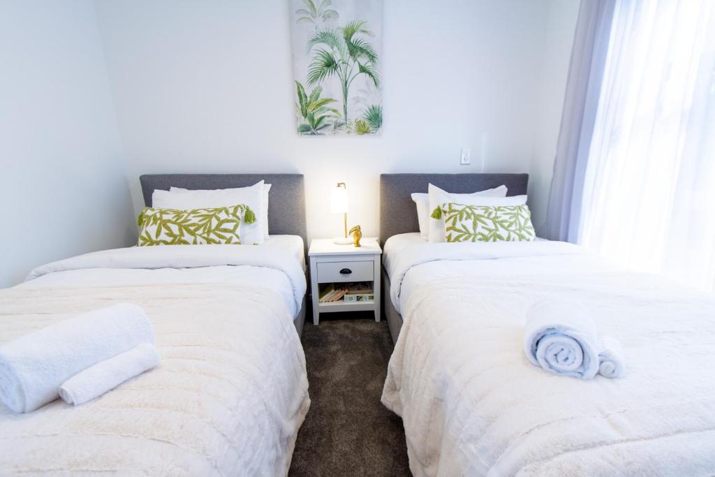 two twin beds in a room with white sheets at Stylish 2-Bedroom Haven Next to Hagley Park in Christchurch