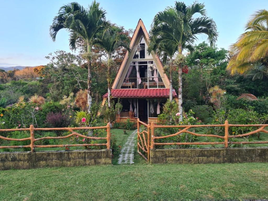 una pequeña casa con una valla y palmeras en Casa El Jardín, en Piedras