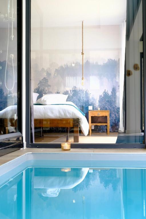 - une chambre avec un lit et une piscine dans l'établissement Au p'tit bonheur, à Rothbach