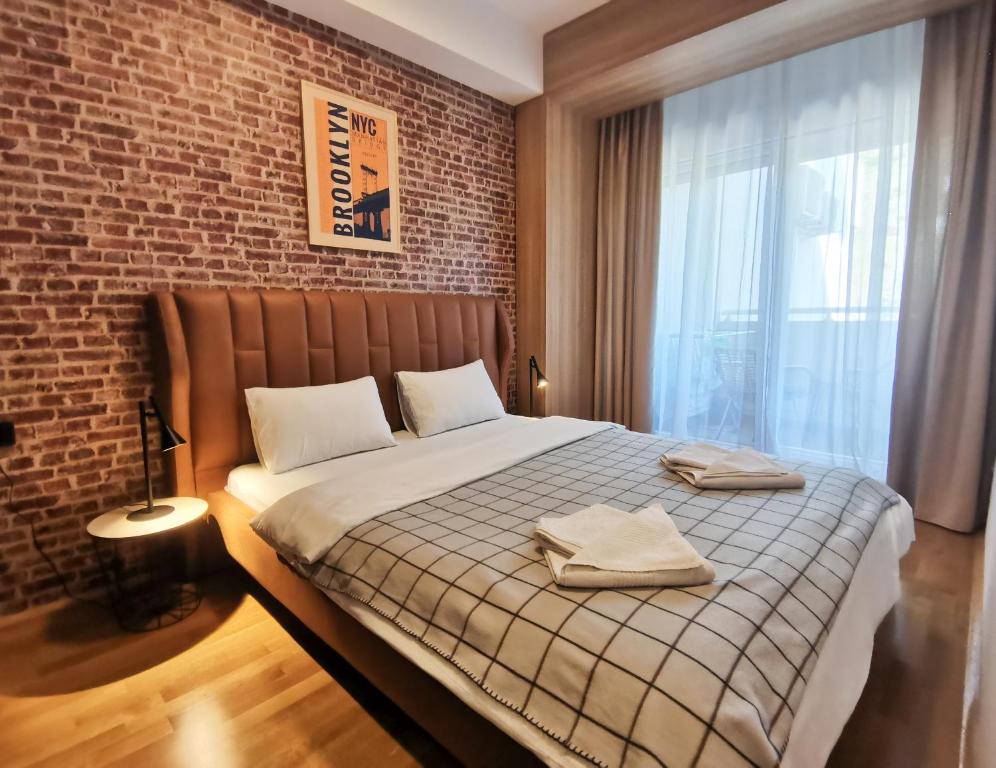 1 dormitorio con 1 cama grande y pared de ladrillo en Cozy One-Bedroom Apartment at Ljubovic Park, en Podgorica