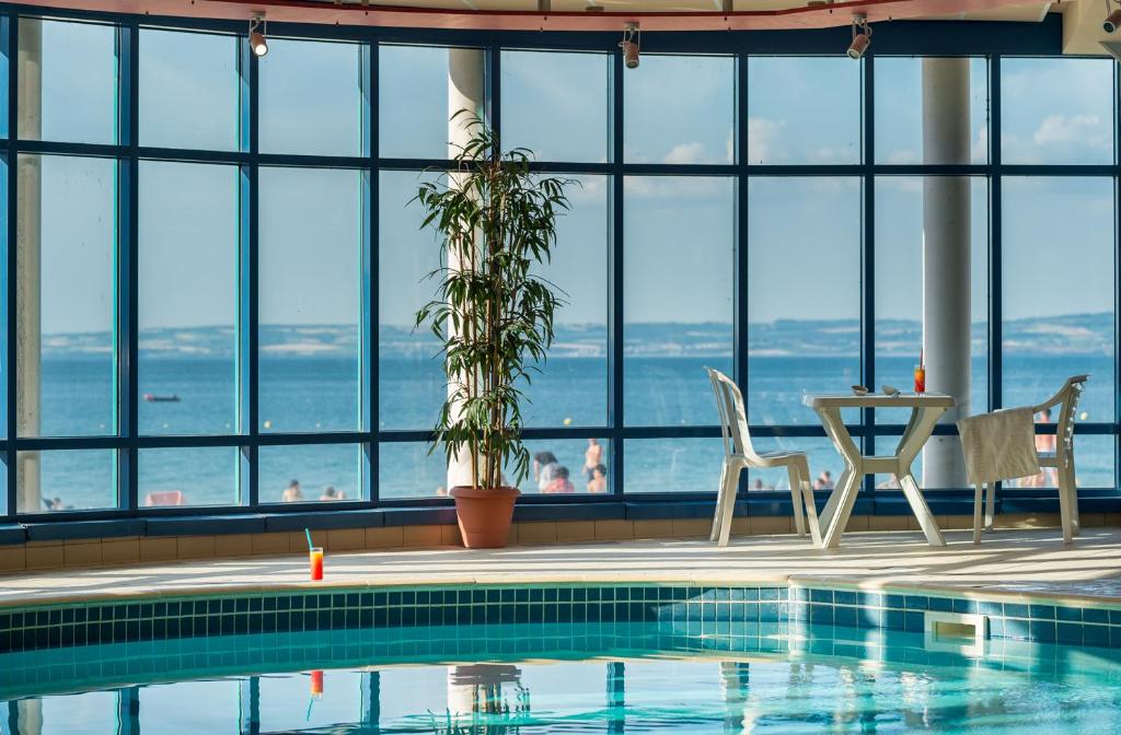 a swimming pool with a view of the ocean from a building at Village Vacances 3* Ternélia Les Résidences d'Armor in Douarnenez