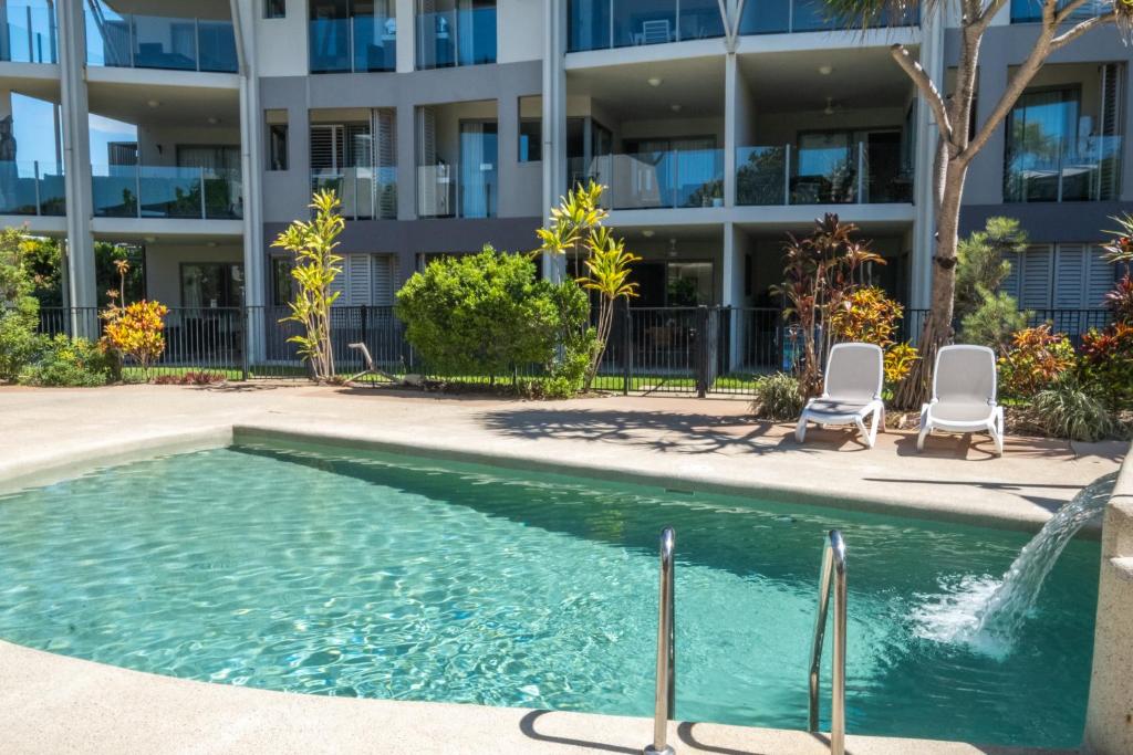 a swimming pool with two chairs and a building at Pavillions on 1770 in Agnes Water