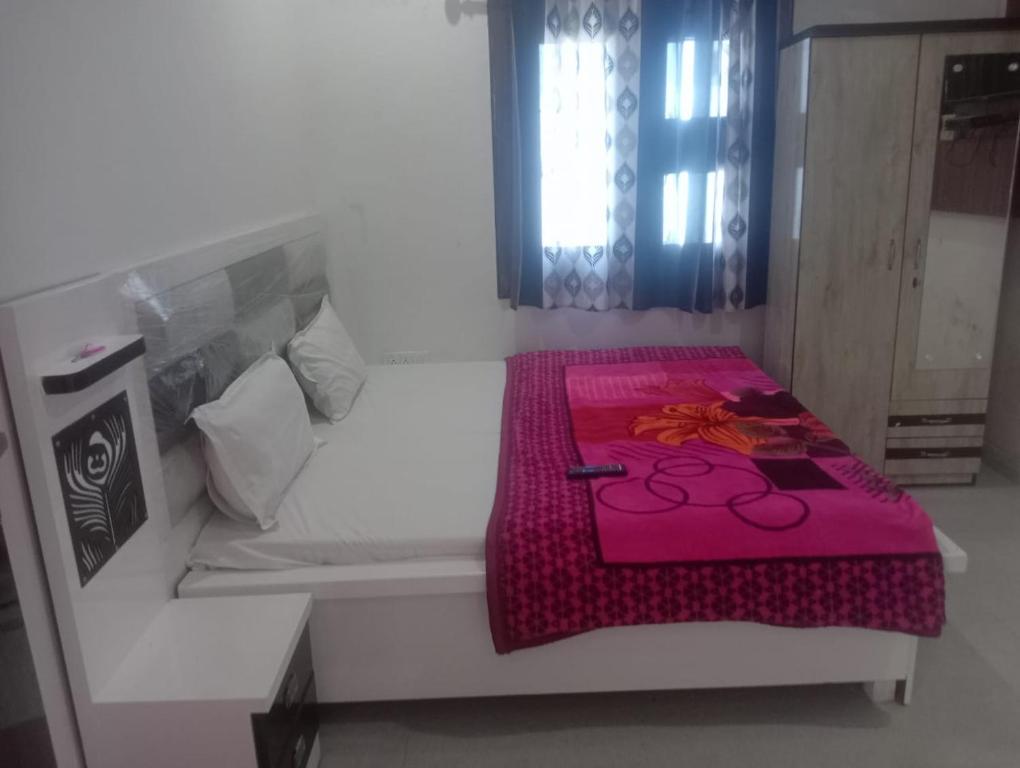 a room with a bed with a pink blanket on it at Gopi Dham Hotel in Vrindāvan