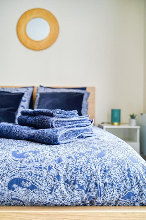 three blue towels stacked on top of a bed at Logement Noah in Courcouronnes