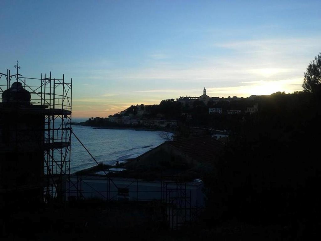a view of a beach with the ocean and the sunset at Hotel Svizzera in Arma di Taggia