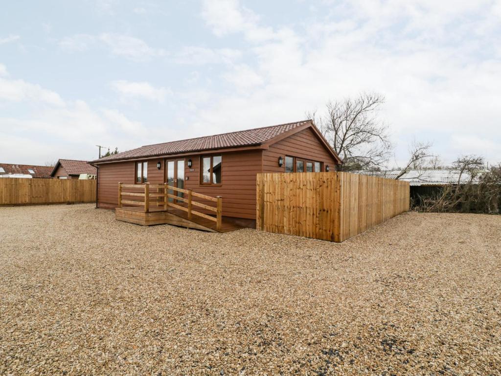 a house with a wooden fence in a yard at Bluebell Lodge, Meadow view lodges in Burnham on Sea