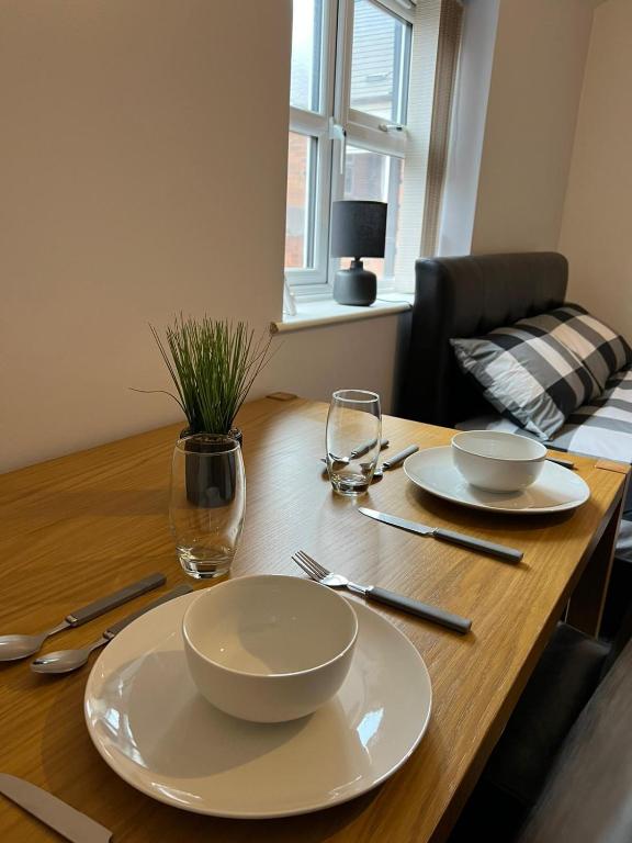 a wooden table with two white bowls and plates on it at No.9 Cosy Private Studio in Moseley, Birmingham in Birmingham