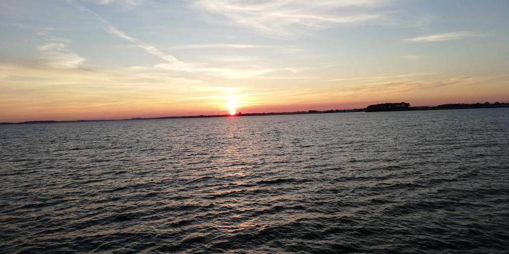 una puesta de sol sobre un gran cuerpo de agua en Ferienwohnung Am Stadtrand Garz Rügen, en Garz