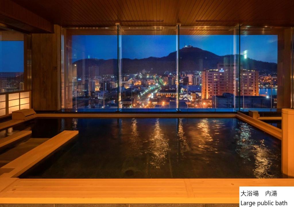 a swimming pool with a view of a city at night at La Vista Hakodate Bay Annex in Hakodate