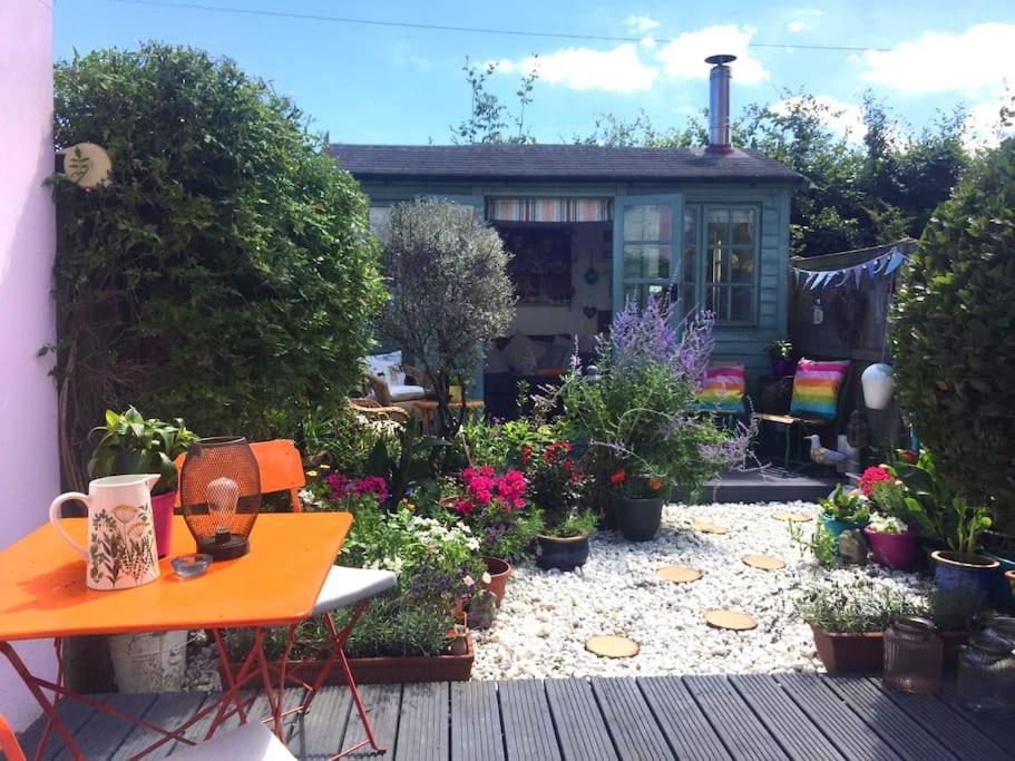 um jardim com uma mesa e um monte de plantas em Heart house fisherman’s cottage em Kent