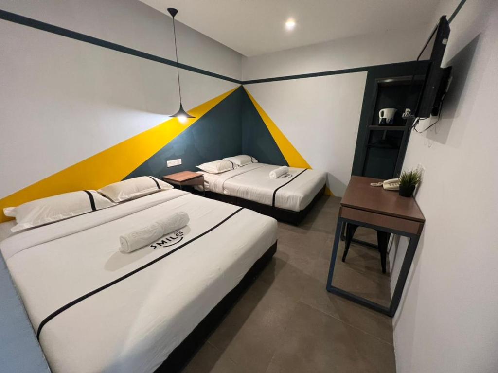 a room with two beds and a table with a desk at Smile Hotel Cheras Sri Permaisuri in Kuala Lumpur
