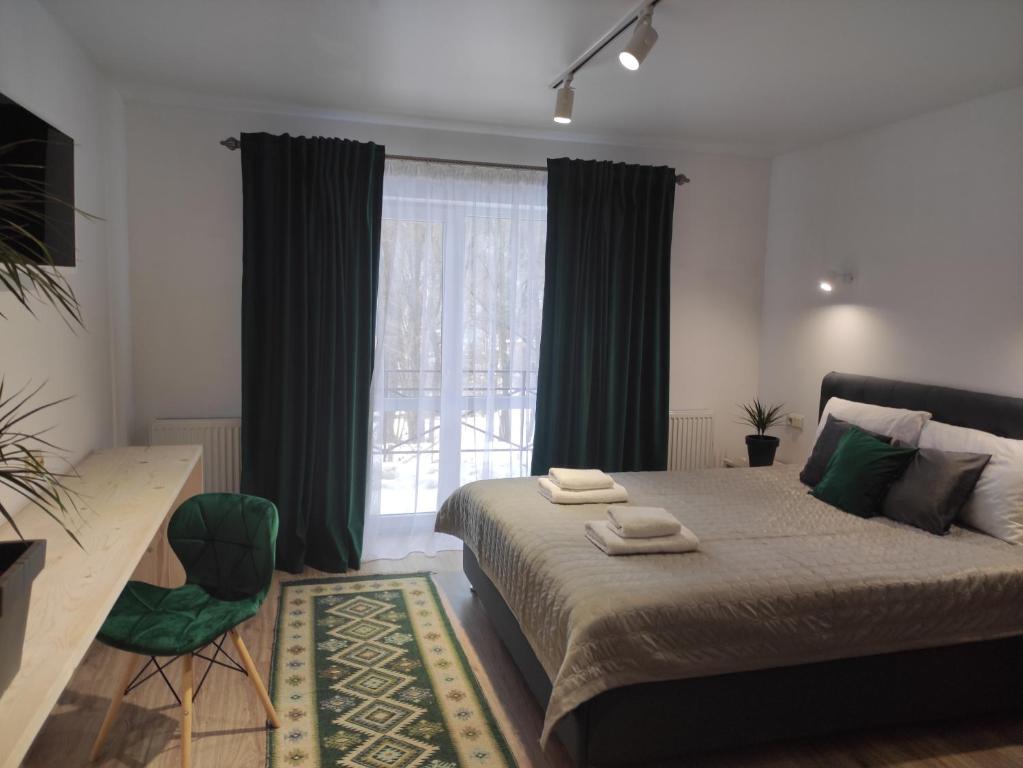 a bedroom with a bed with green curtains and a window at Guest House Svitliza in Yaremche