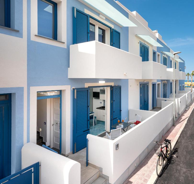 a building with blue and white doors and a balcony at IL FARO E LA LUNA Beach Apartments in San Vito lo Capo