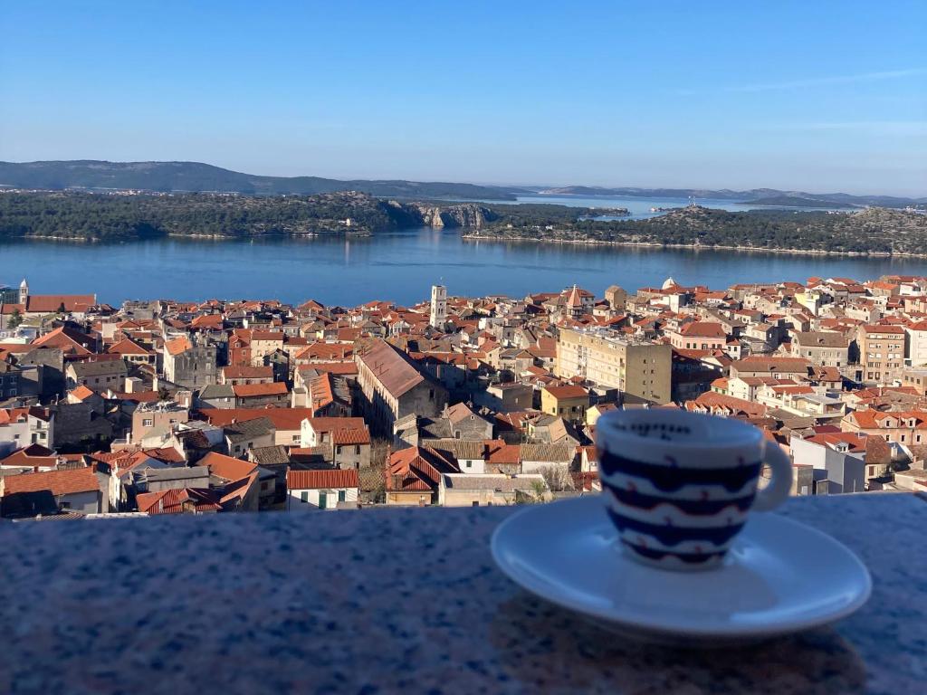 una tazza di caffè seduta su un cornicione che domina una città di Apartment Barone Šibenik - city view & free parking a Šibenik