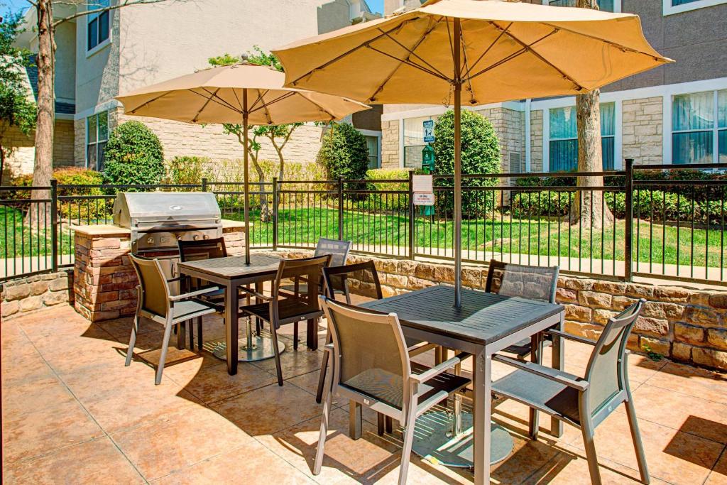 un patio con mesas, sillas y sombrillas en Residence Inn Dallas Park Central, en Dallas