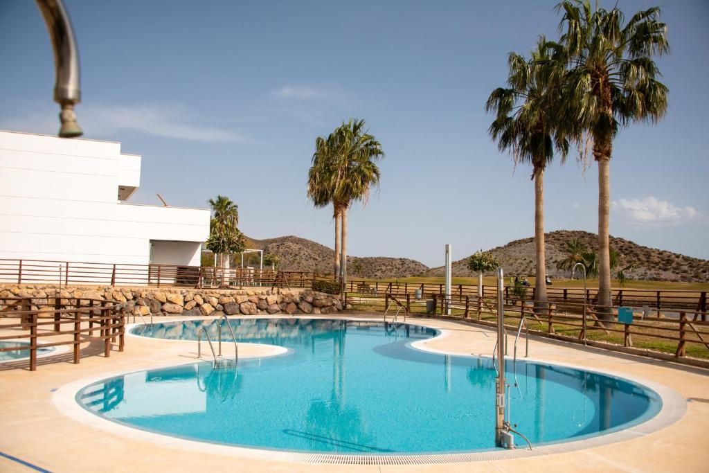 uma piscina com palmeiras e uma cerca em Beautiful Apartment Casa Mundo Aguilón em San Juan de los Terreros