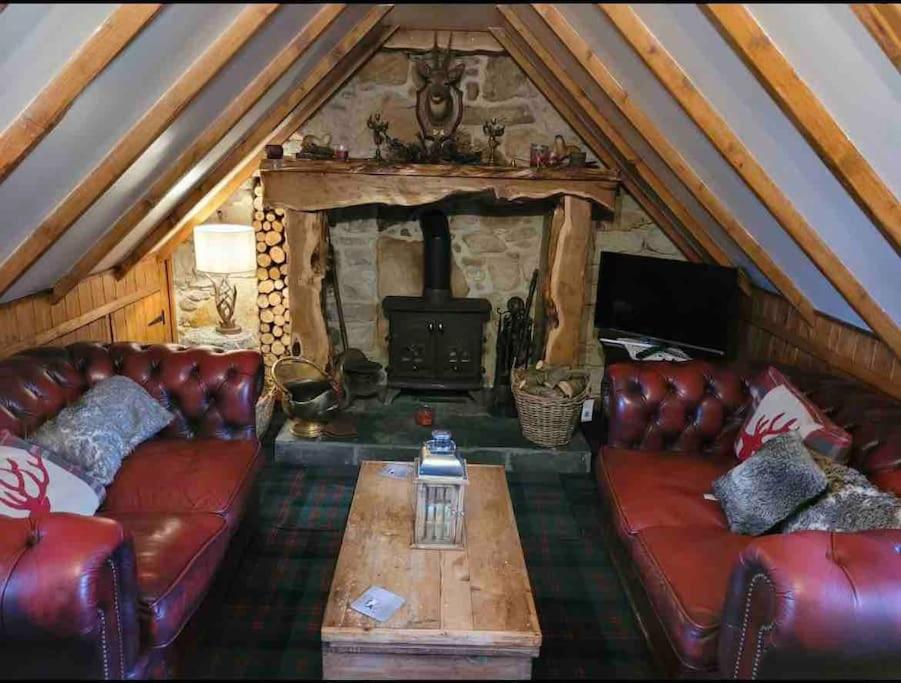 sala de estar con sofás de cuero y chimenea en Baidland Escapes 2 bedroom cottage With hot tub, en Dalry