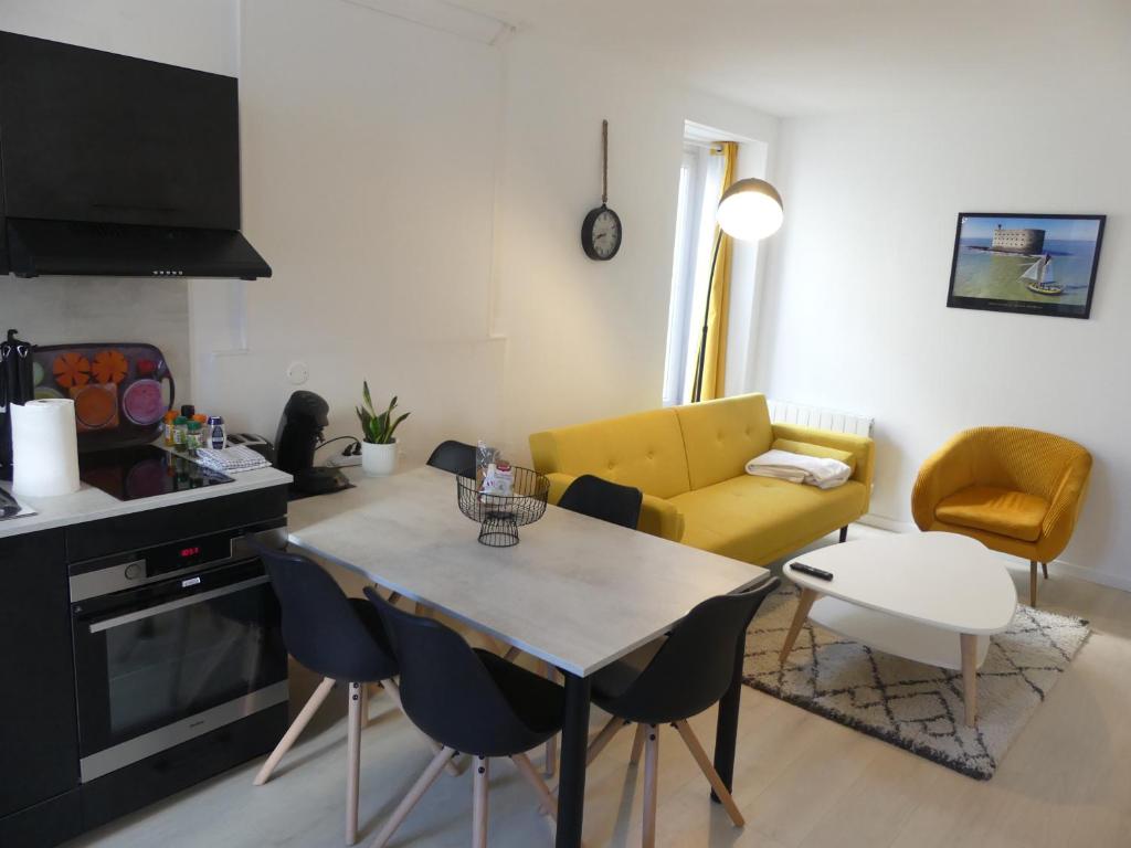 uma sala de estar com uma mesa e um sofá amarelo em Superbe Maison Rénovée en Centre-ville em Saint-Pierre-dʼOléron