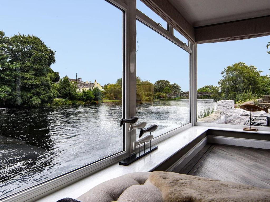 a room with a large window looking out at a river at Creebank in Newton Stewart